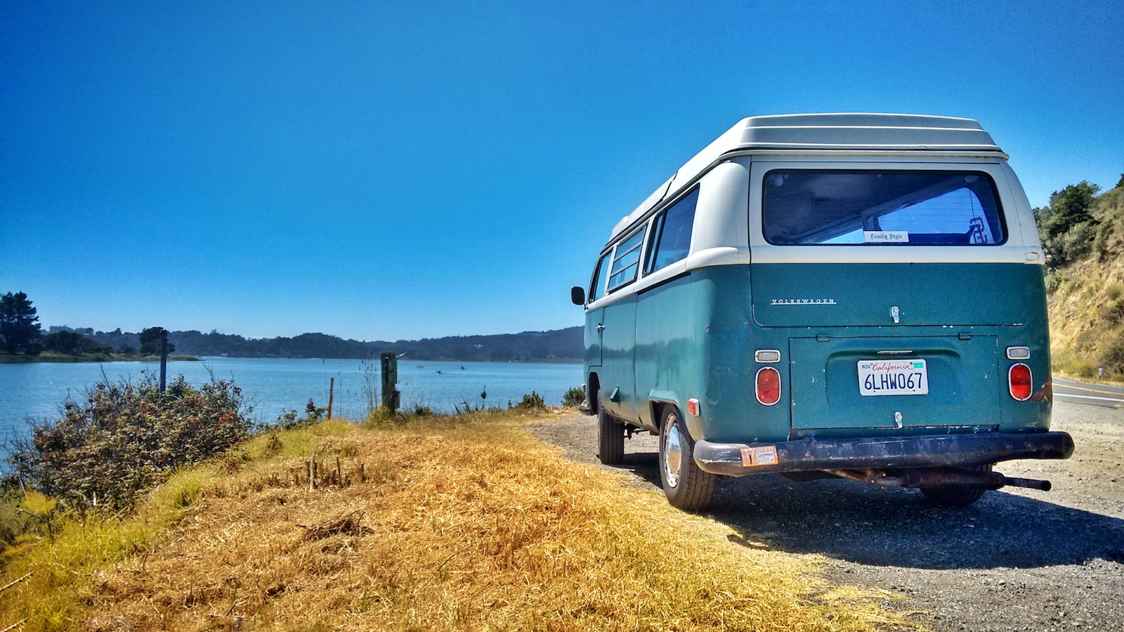 vw microbus, a van parked on the side of a road next to a body of water