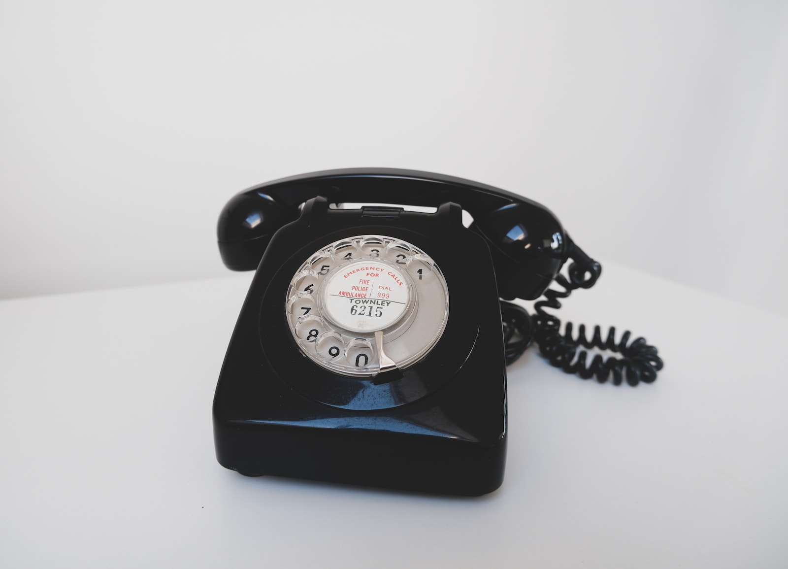Prevalent in the 60s and 70s, black rotary phone on white surface