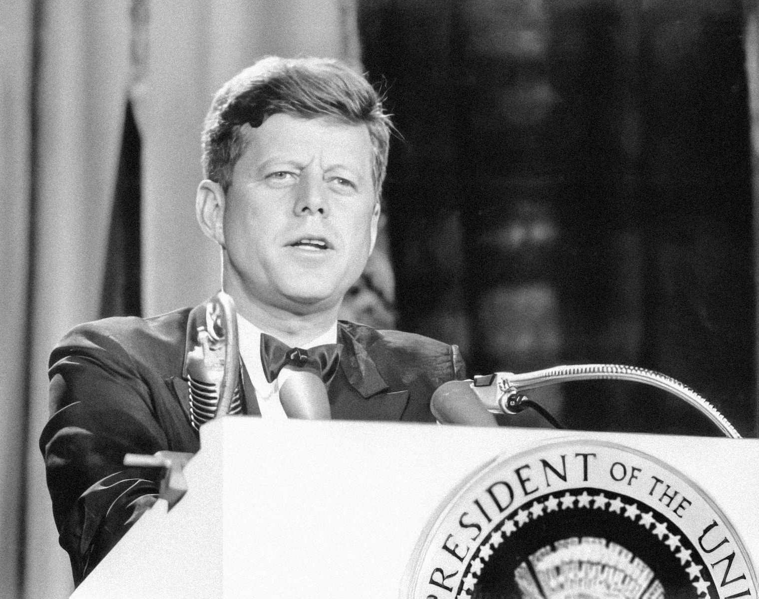 Kennedy assisnation, a man in a suit and tie standing at a podium