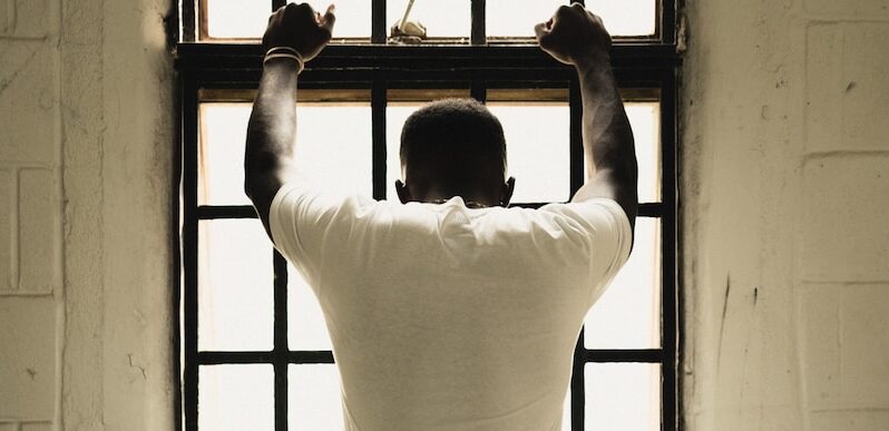 man in white t-shirt standing in front of window